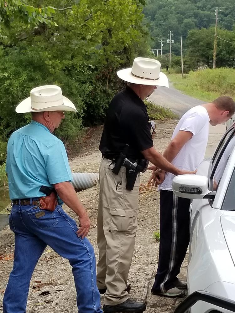 man in handcuffs against vehicle