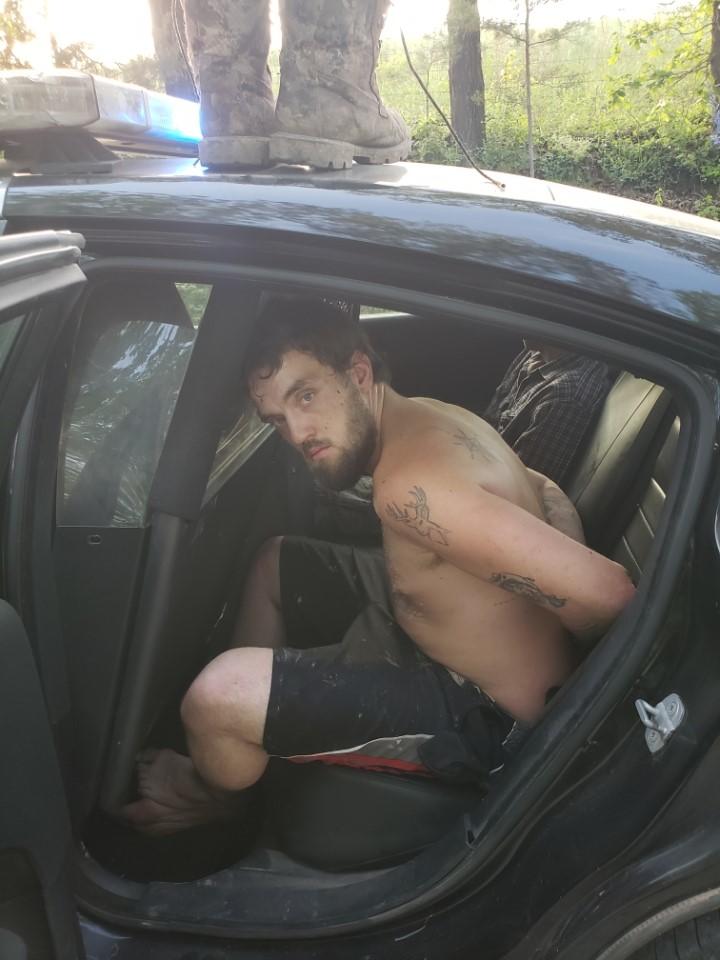 Austin Sharp arrested and sitting in the back on an officers vehicle.