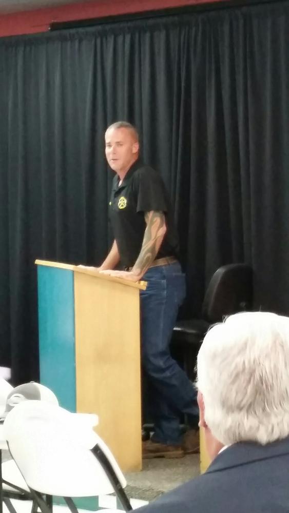 man standing at podium in black shirt
